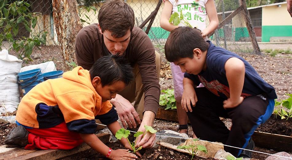 Rutgers Global – Peace Corps, volunteer plants tree with local children